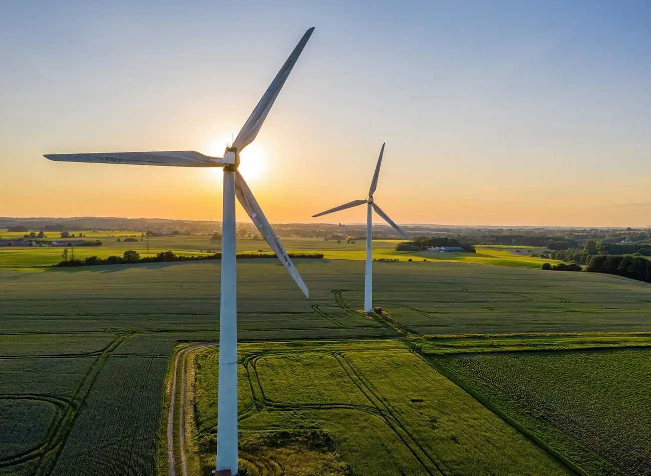 Aeral view of two wind turbines at sunset.